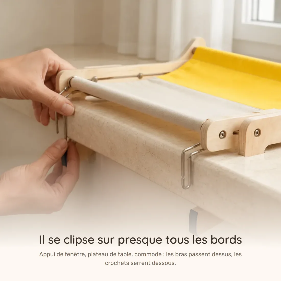 It clamps to almost any edge — two hands engaging the hooks of the wooden-frame perch under a window sill